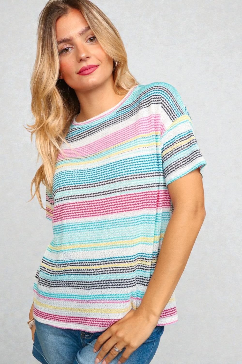 Woman wearing a colorful striped shirt against a gray background