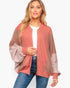 A woman modeling a color-blocked bomber jacket with a dusty rose front panel and sleeves, and light pink sheer mesh side panels, worn over a white t-shirt and blue jeans against a plain white background.