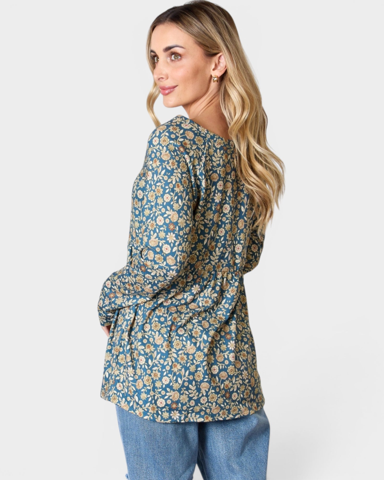 Woman wearing a floral blouse and jeans on a white background
