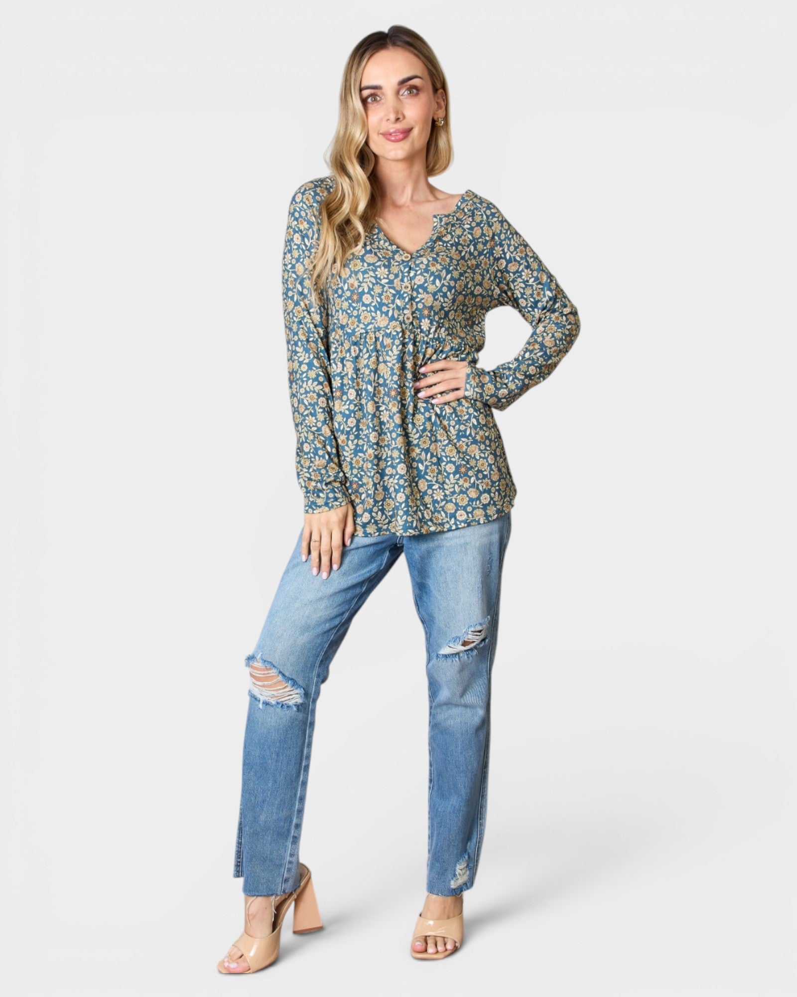 Woman wearing a floral long-sleeve top and blue jeans on a white background