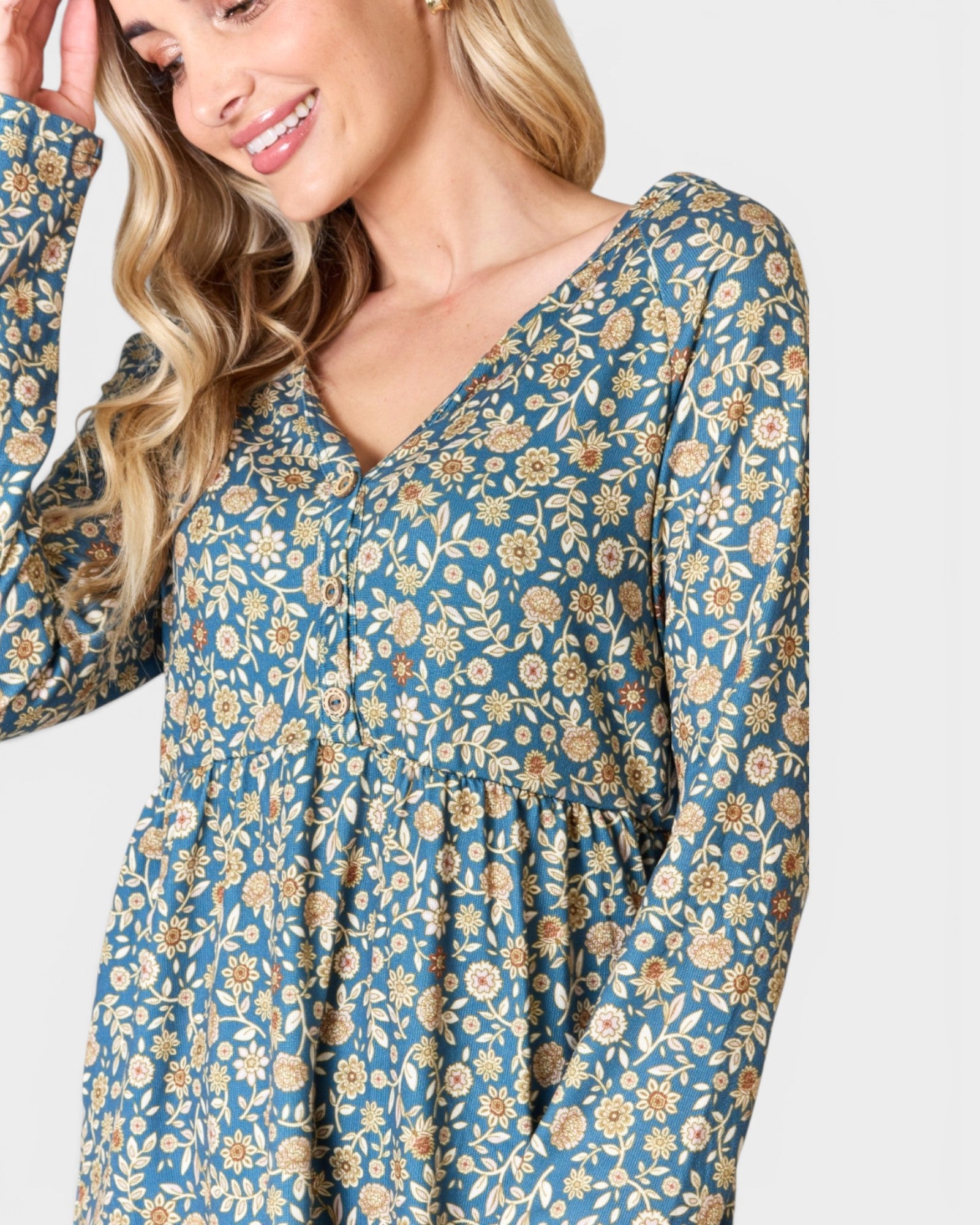 Woman wearing a blue floral dress with long sleeves on a white background