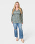 Woman wearing a floral blouse and ripped jeans on a white background