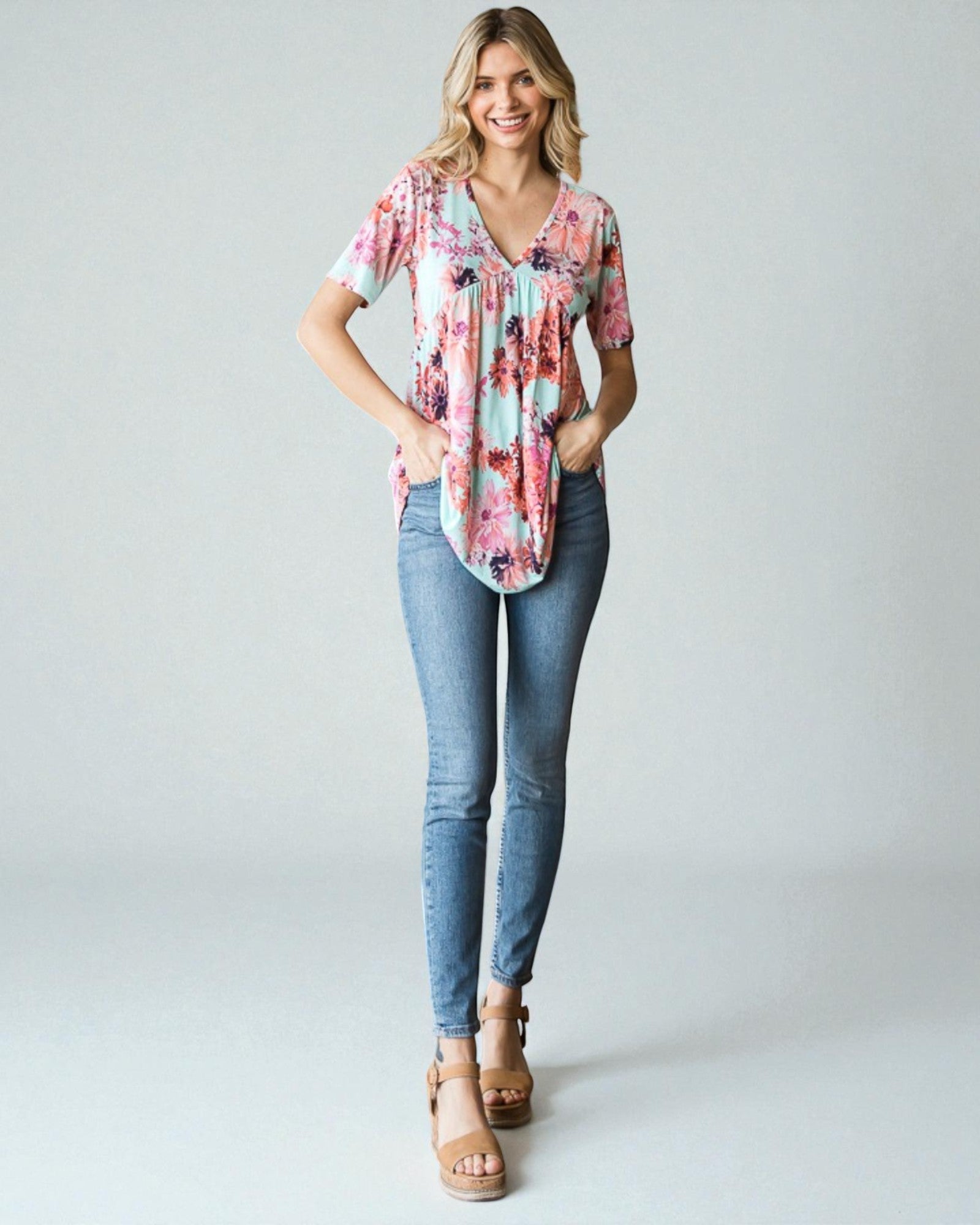 Woman wearing a floral blouse and blue jeans on a plain background