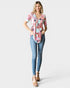 Woman wearing a floral blouse and blue jeans on a white background