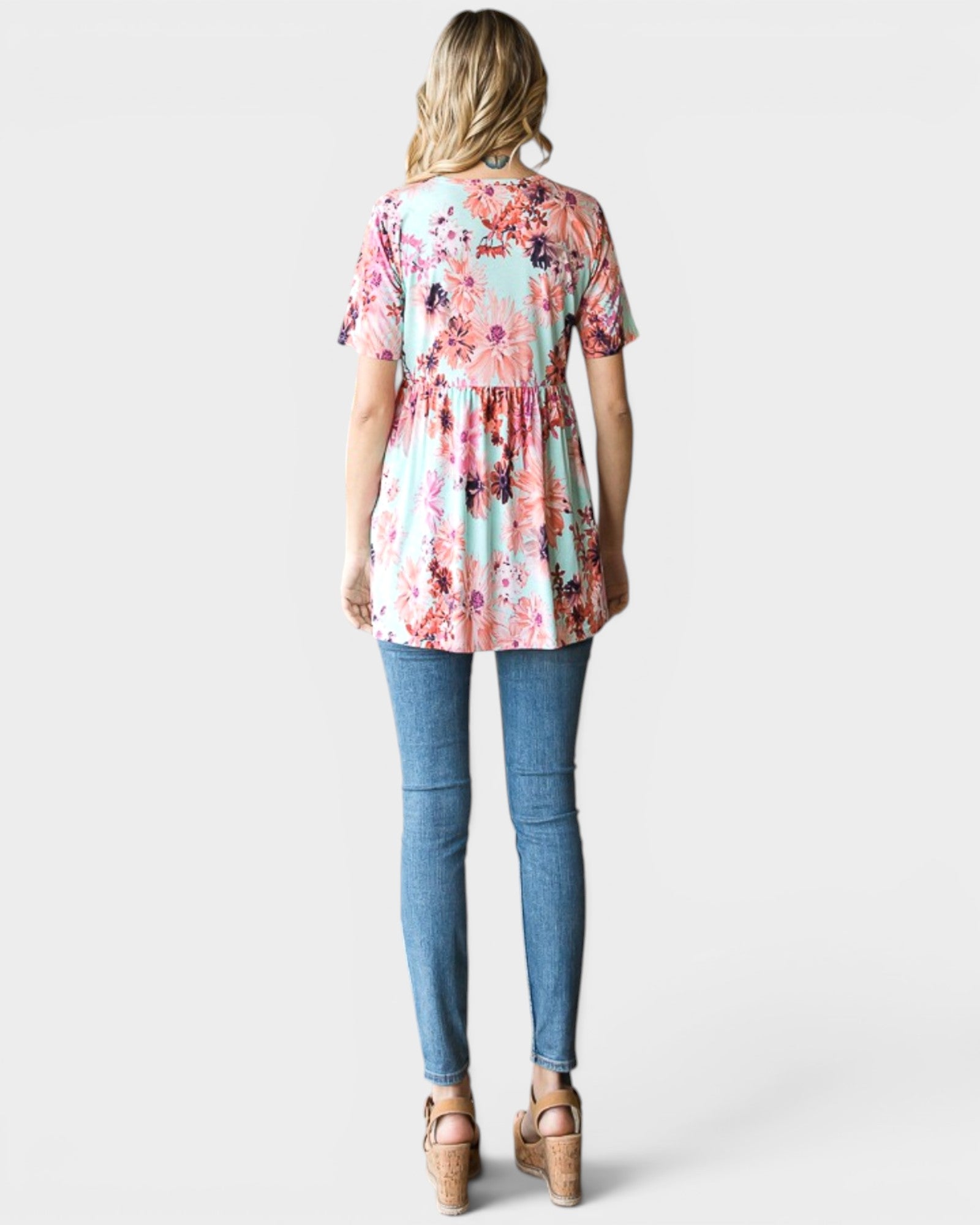 Woman wearing a floral top and blue jeans on a white background