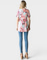 Woman wearing a floral top and blue jeans on a white background