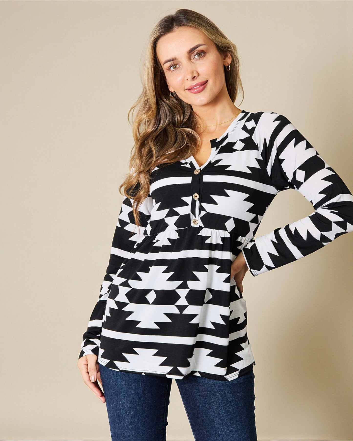 Woman wearing a black and white patterned long-sleeve top against a beige background