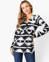 A woman modeling a black and white geometric patterned long-sleeve top with a split neckline and half-zip front, paired with blue jeans against a plain white background.