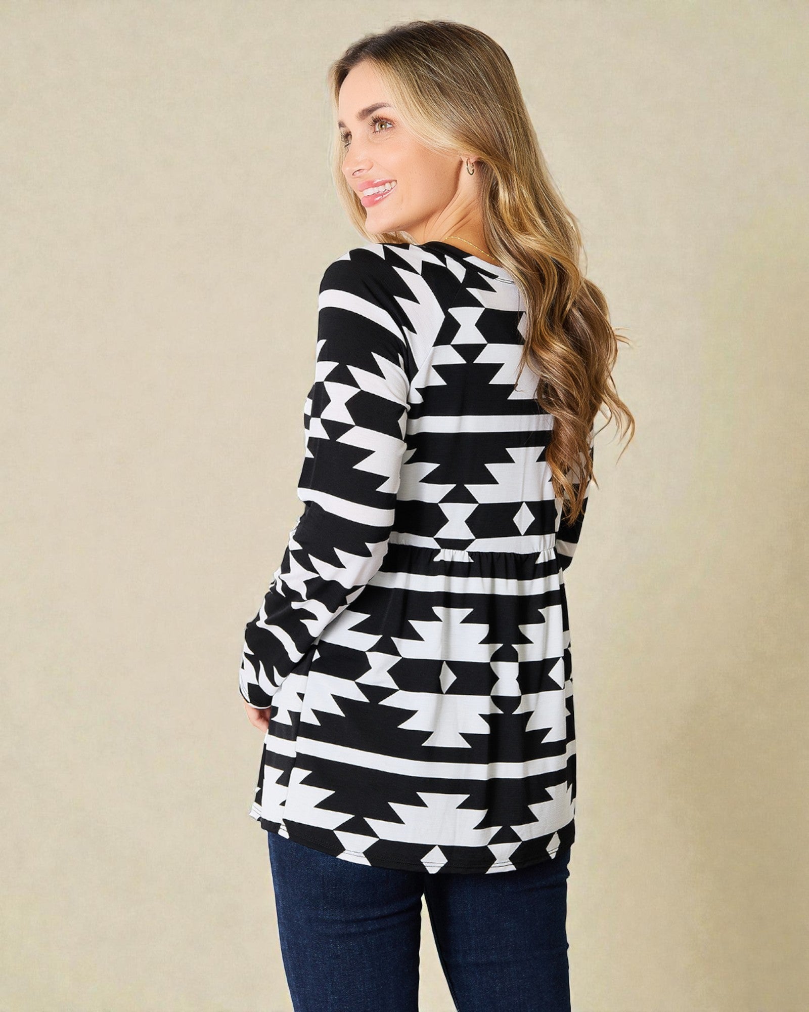 Woman wearing a black and white patterned cardigan against a beige background