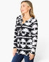 A woman wearing a black and white geometric patterned long-sleeve top with a split neckline and drawstring, paired with blue jeans, against a plain white studio background.