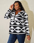 Woman wearing a black and white patterned long-sleeve top against a plain background