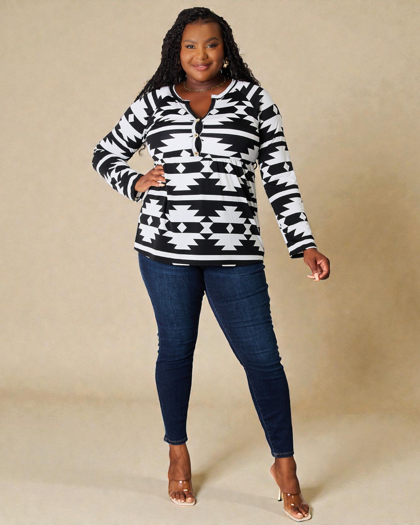 Woman wearing a black and white patterned sweater and blue jeans on a beige background