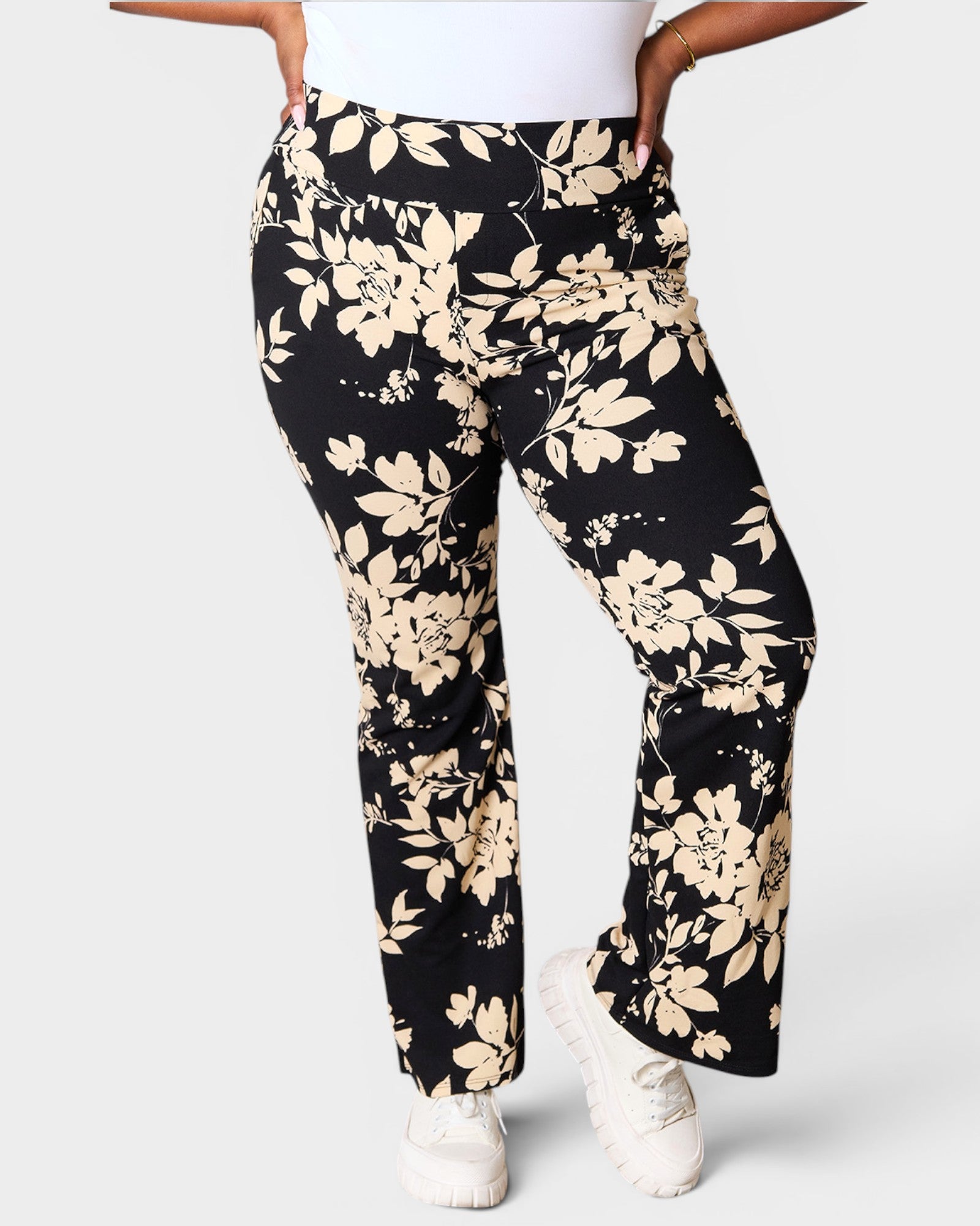 Black pants with beige floral pattern worn by a person on a white background