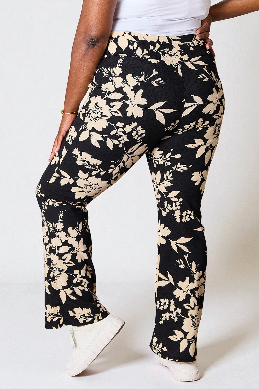 Black floral pants worn by a person on a white background