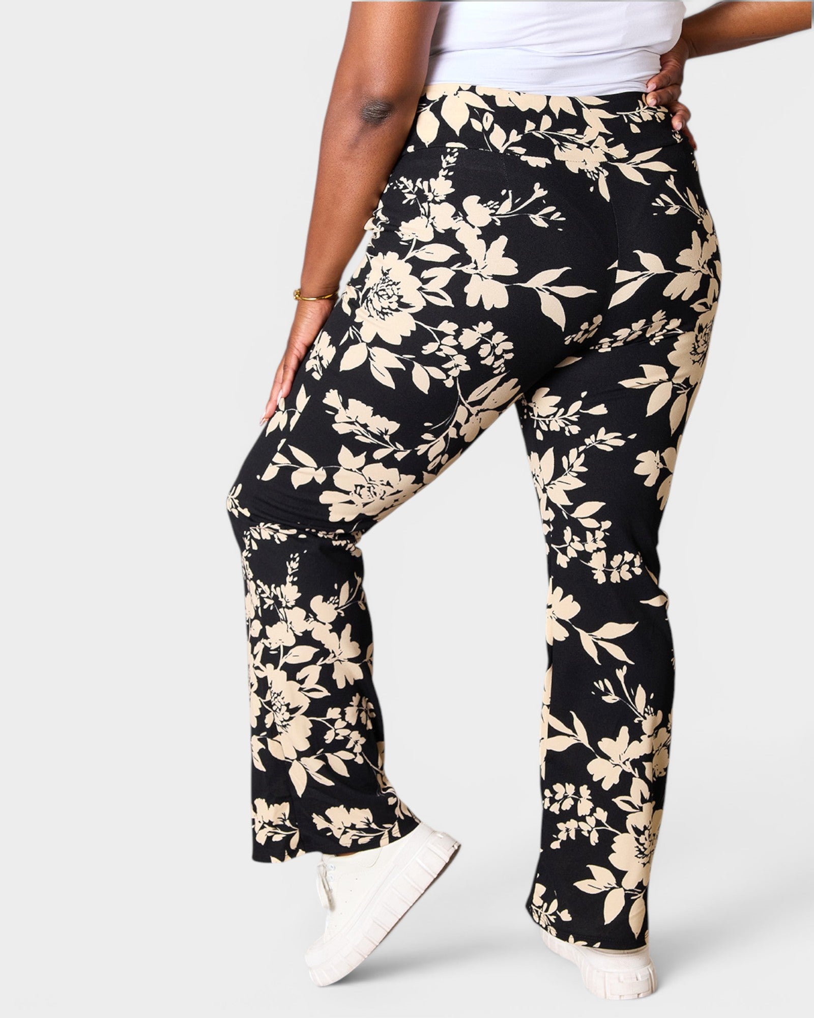 Black floral pants worn by a person on a white background