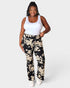 Woman wearing a white tank top and black floral pants on a white background