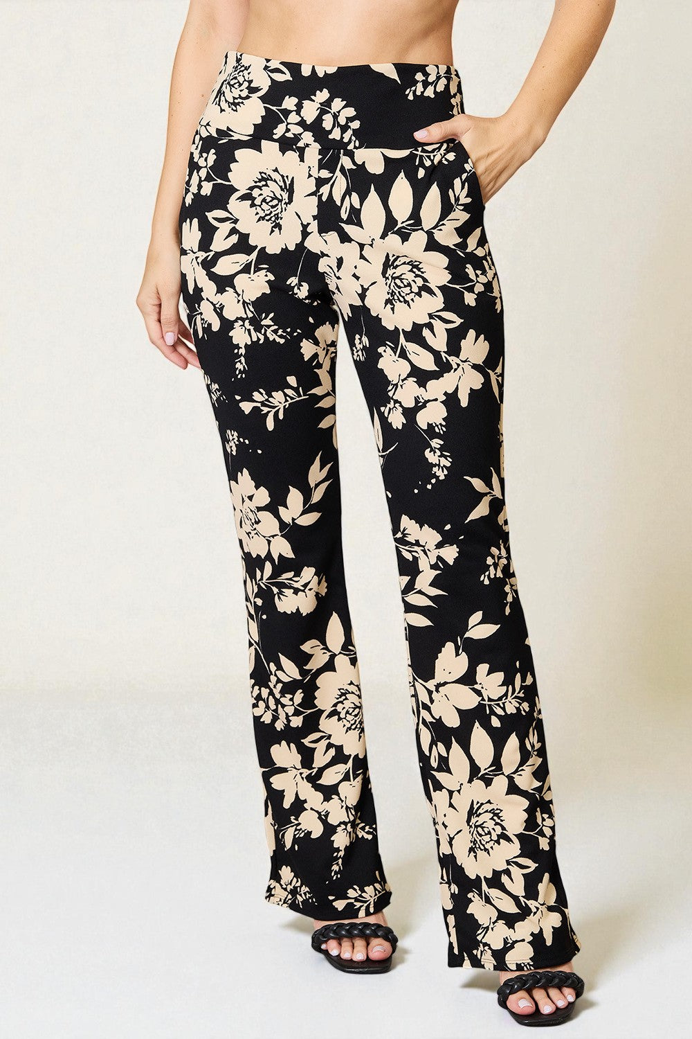 Black floral pants worn by a person on a white background