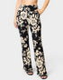 Black pants with beige floral pattern worn by a person on a white background