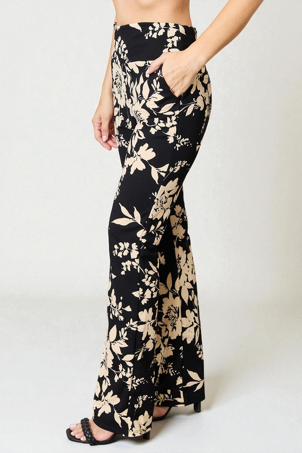 Black floral pants worn by a person on a white background