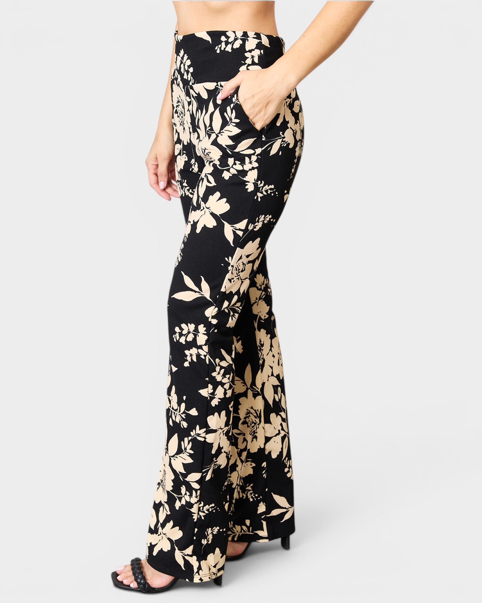 Black floral-patterned pants worn by a person on a white background