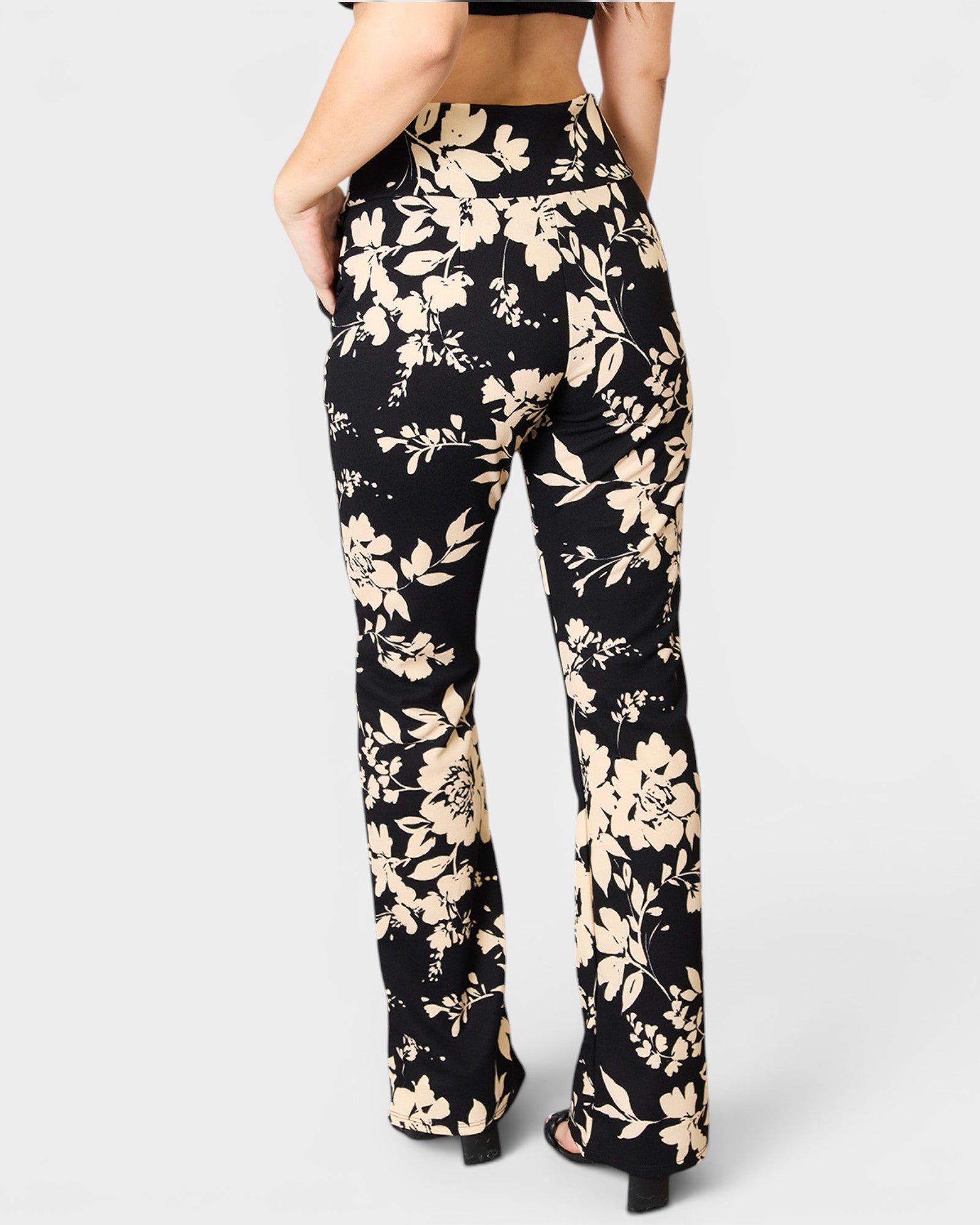 Black pants with beige floral pattern worn by a person on a white background