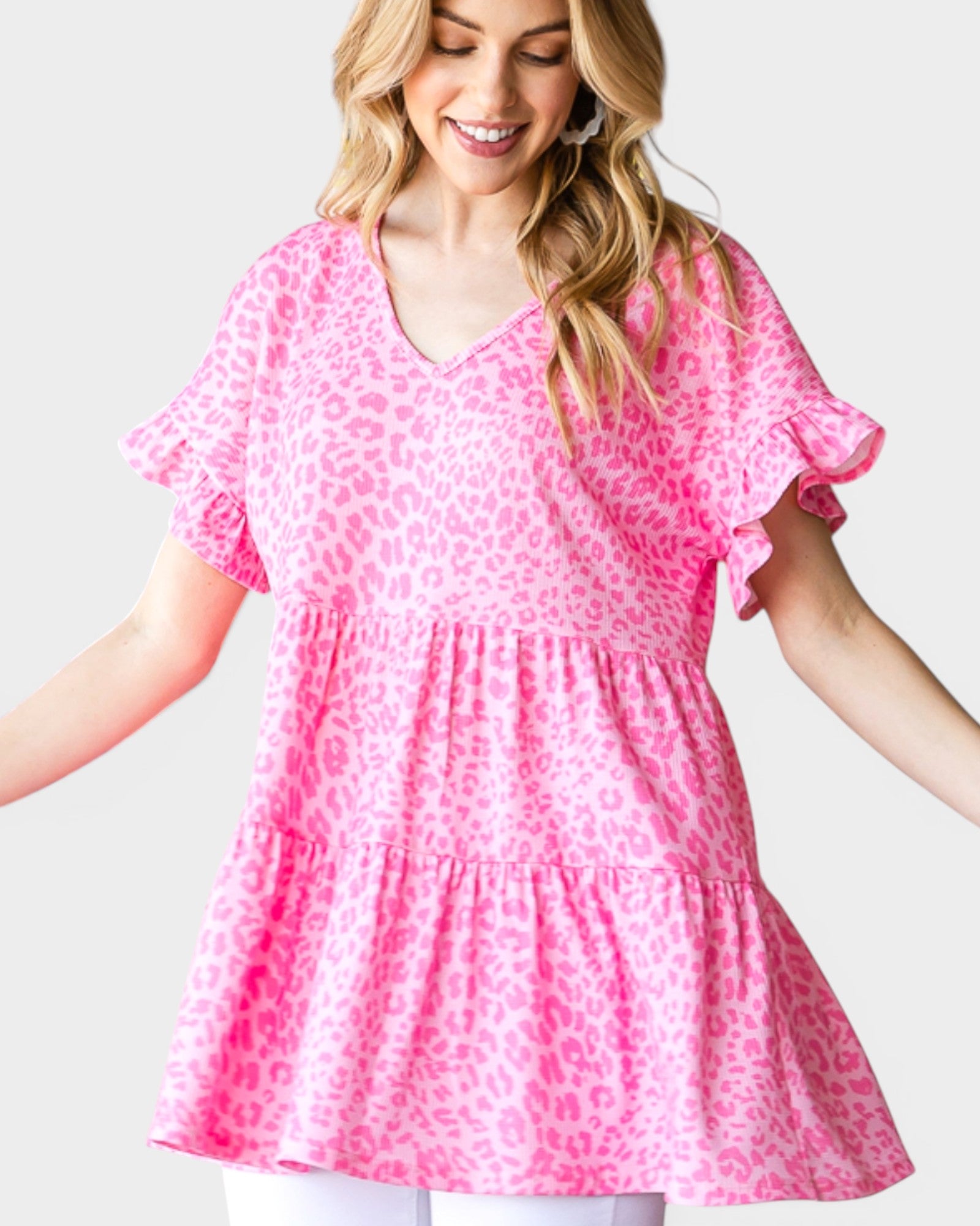 Woman wearing a pink leopard print top on a light gray background