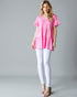Woman wearing a pink floral top and white pants on a gray background