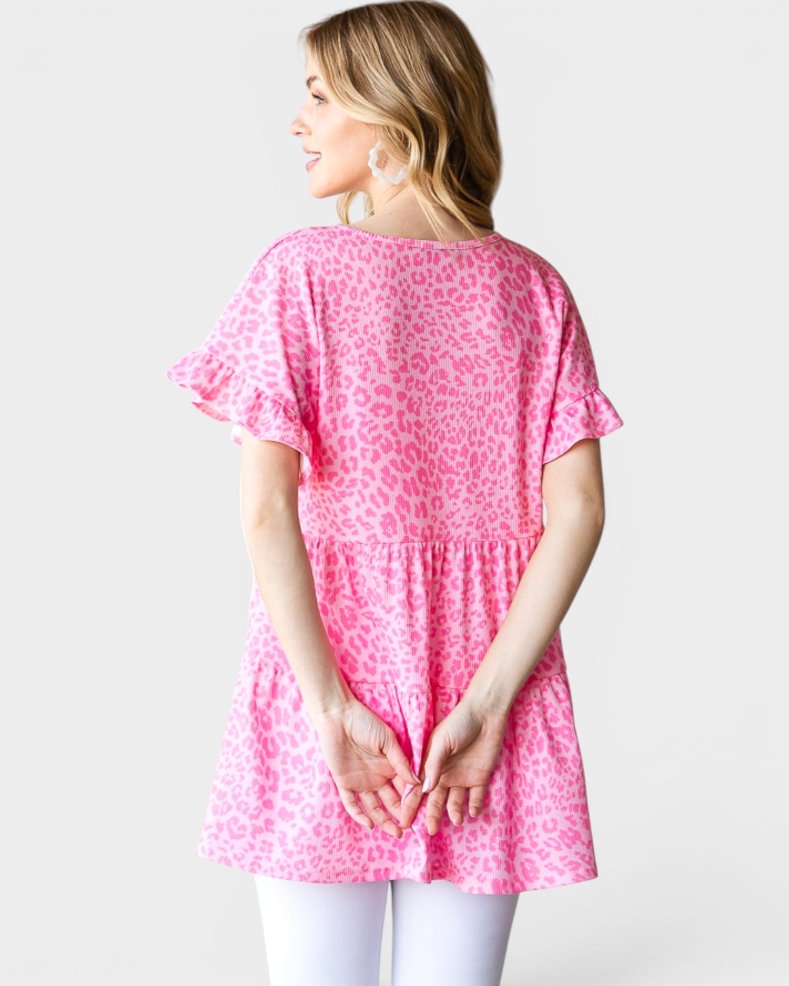 Woman wearing a pink leopard print top against a white background