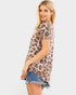Woman wearing a leopard print top and denim shorts on a white background