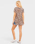 Woman wearing a leopard print dress with denim shorts on a white background