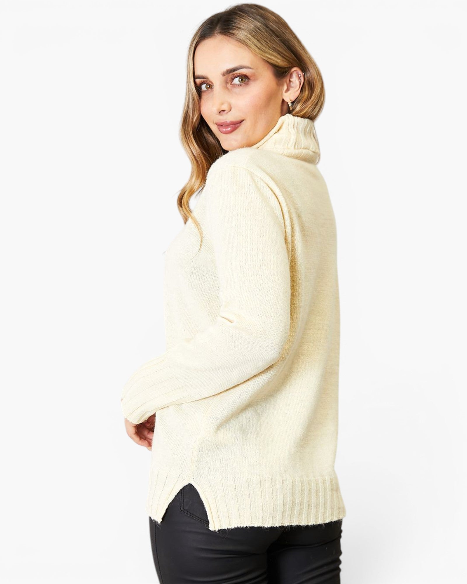 A woman wearing a cream-colored knit turtleneck sweater, shown from a side-back angle against a plain white studio background.