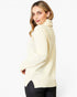 A woman wearing a cream-colored knit turtleneck sweater, shown from a side-back angle against a plain white studio background.
