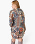 A woman shown from the back wearing a hooded longline cardigan with a complex geometric tribal pattern in beige, blue, gray, and rust orange, paired with gray boots against a plain white background.