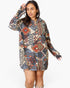 A woman modeling a long-sleeve hooded tunic dress with a colorful geometric tribal pattern in blue, red, orange, and beige, set against a plain white background.