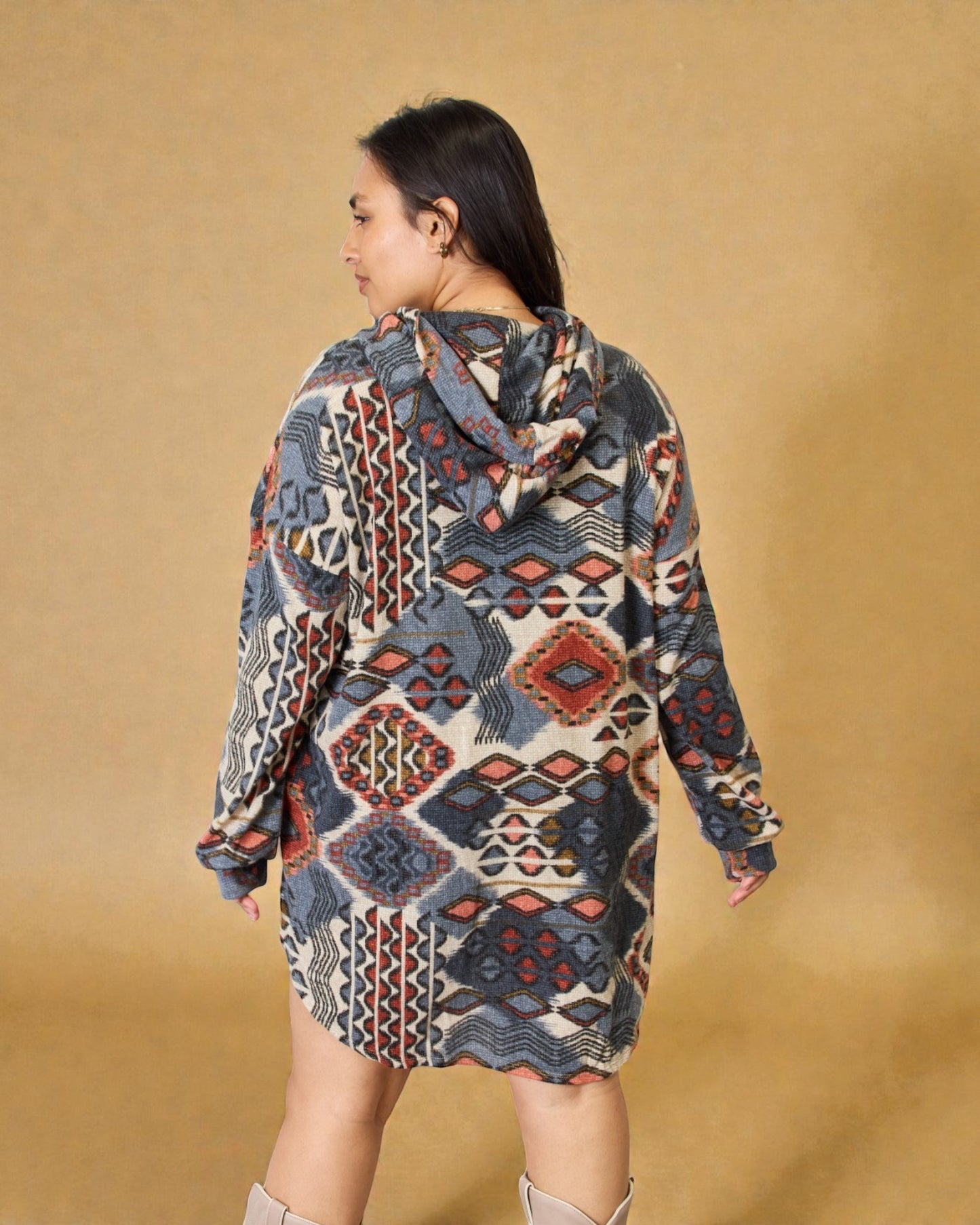 Woman wearing a patterned hoodie dress against a beige background