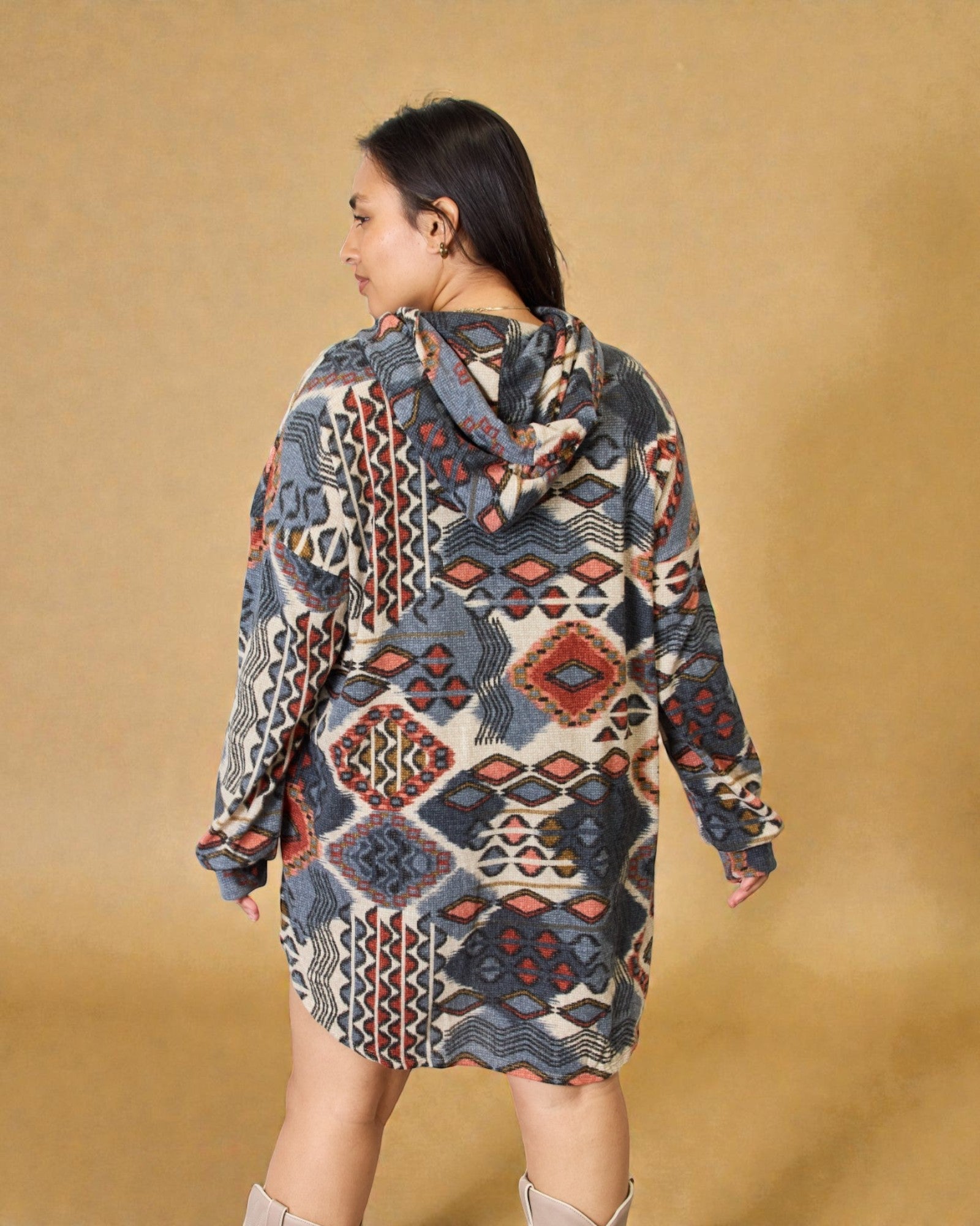 Woman wearing a patterned hoodie dress against a beige background