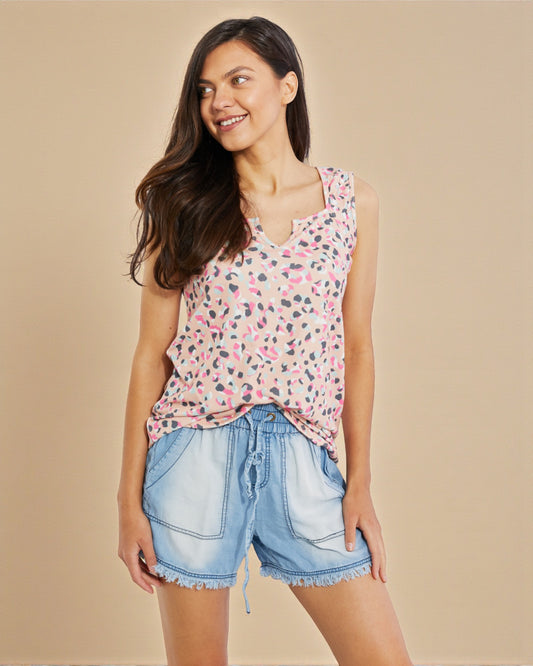 Woman wearing a floral sleeveless top and denim shorts on a beige background
