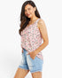 A woman modeling a sleeveless ruffled top with a pink, black, and gray leopard print, paired with light blue denim shorts, against a plain white background.