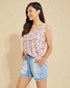 Woman wearing a floral top and denim shorts on a beige background