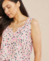 Woman wearing a sleeveless top with a colorful abstract pattern on a beige background