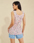 Woman wearing a sleeveless floral top and denim shorts on a beige background