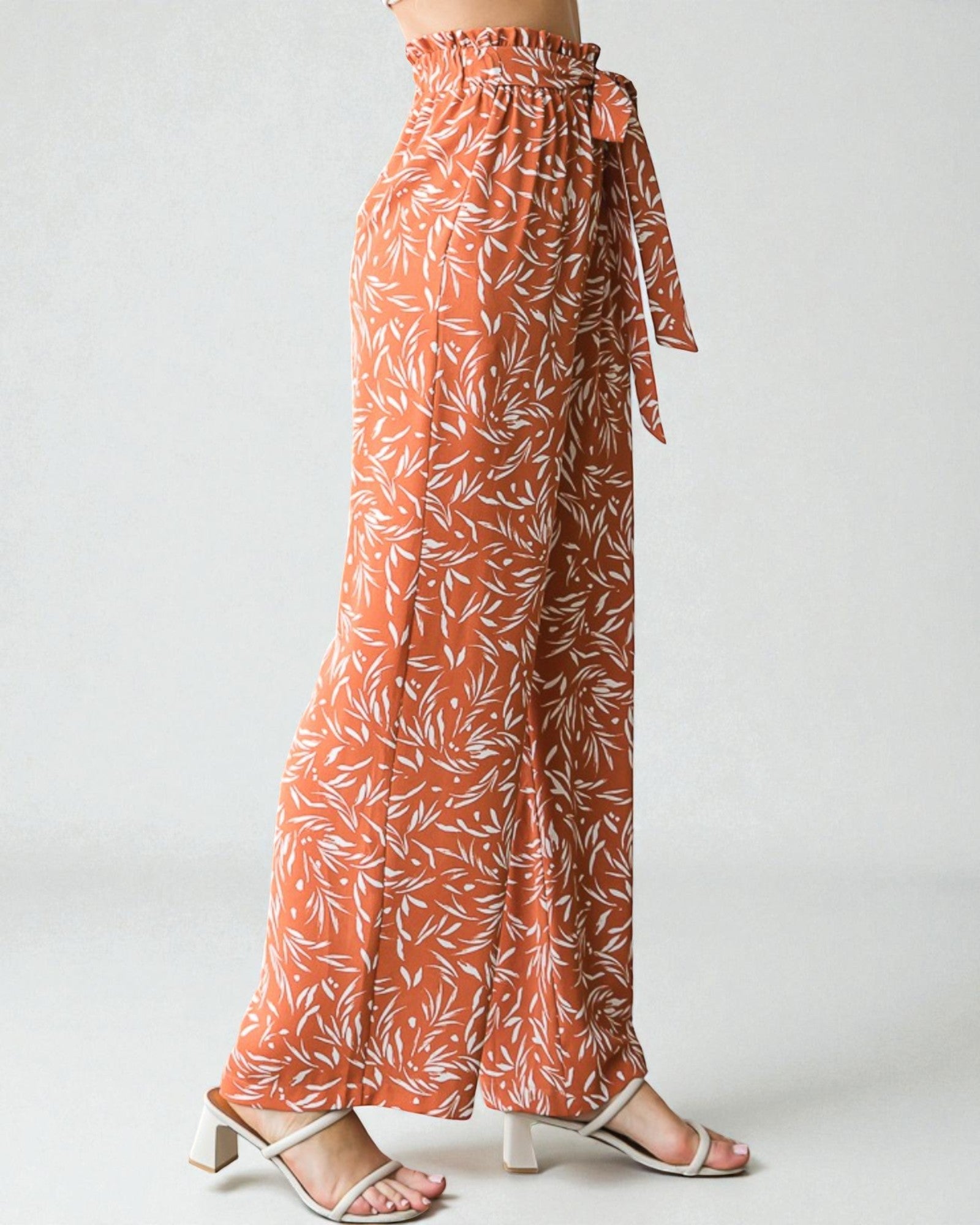 Orange floral patterned pants worn by a person on a white background