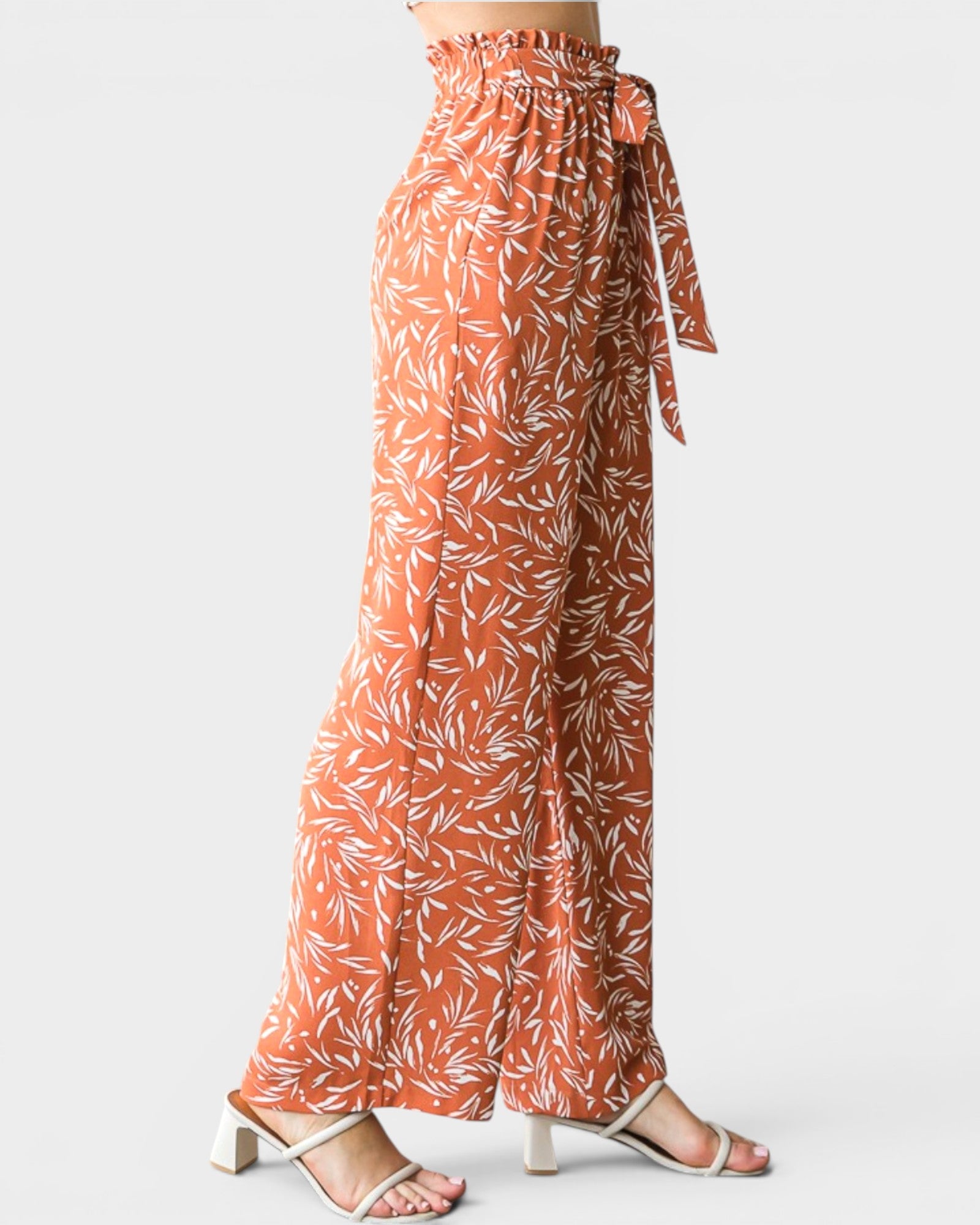 Orange floral patterned pants with a tie waist on a white background