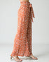 Orange floral patterned pants worn by a person on a white background