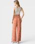 Woman wearing a sleeveless top and patterned pants on a white background