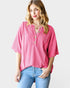 Woman wearing a pink ribbed blouse with button details on a light gray background