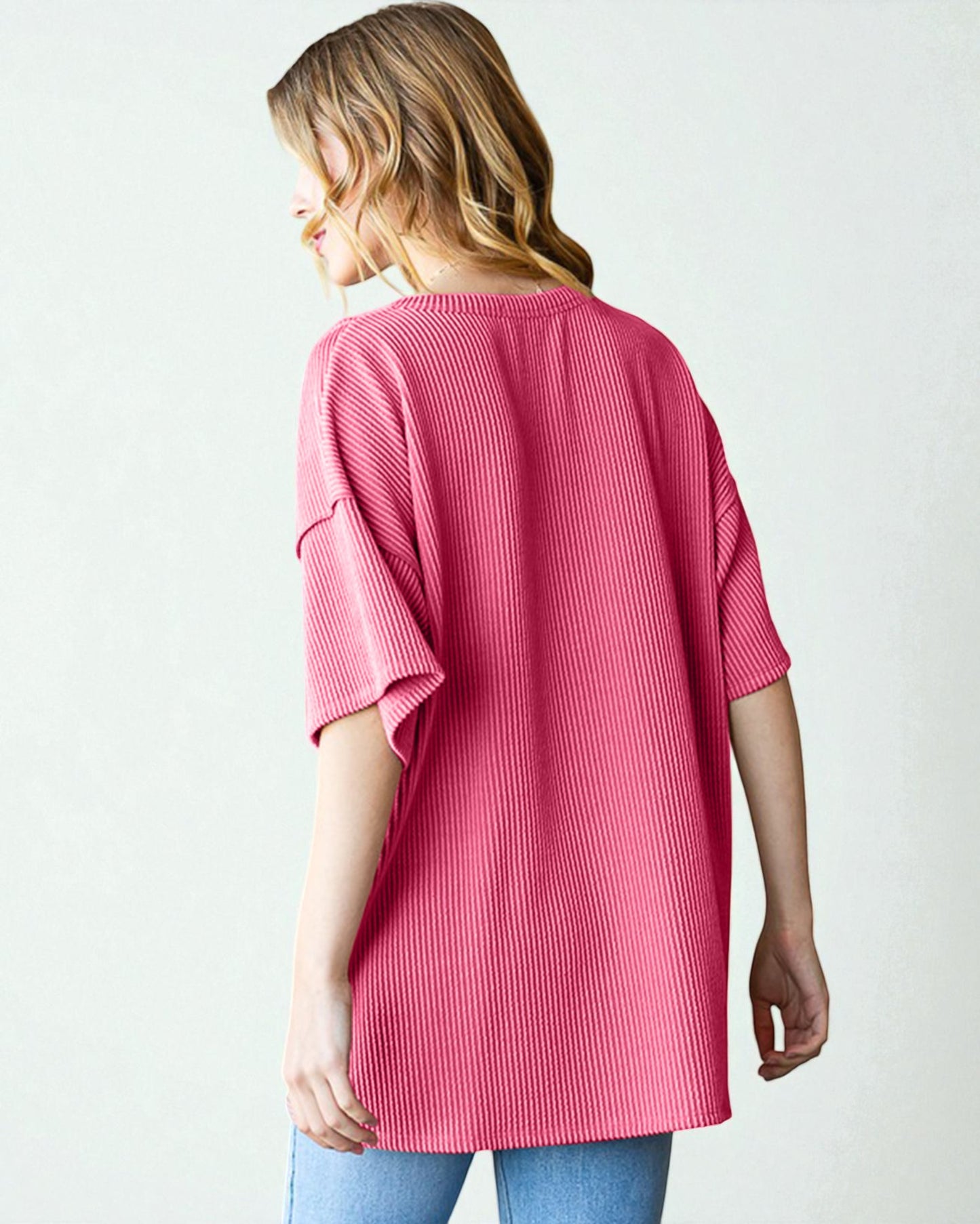 Woman wearing a pink ribbed sweater on a white background