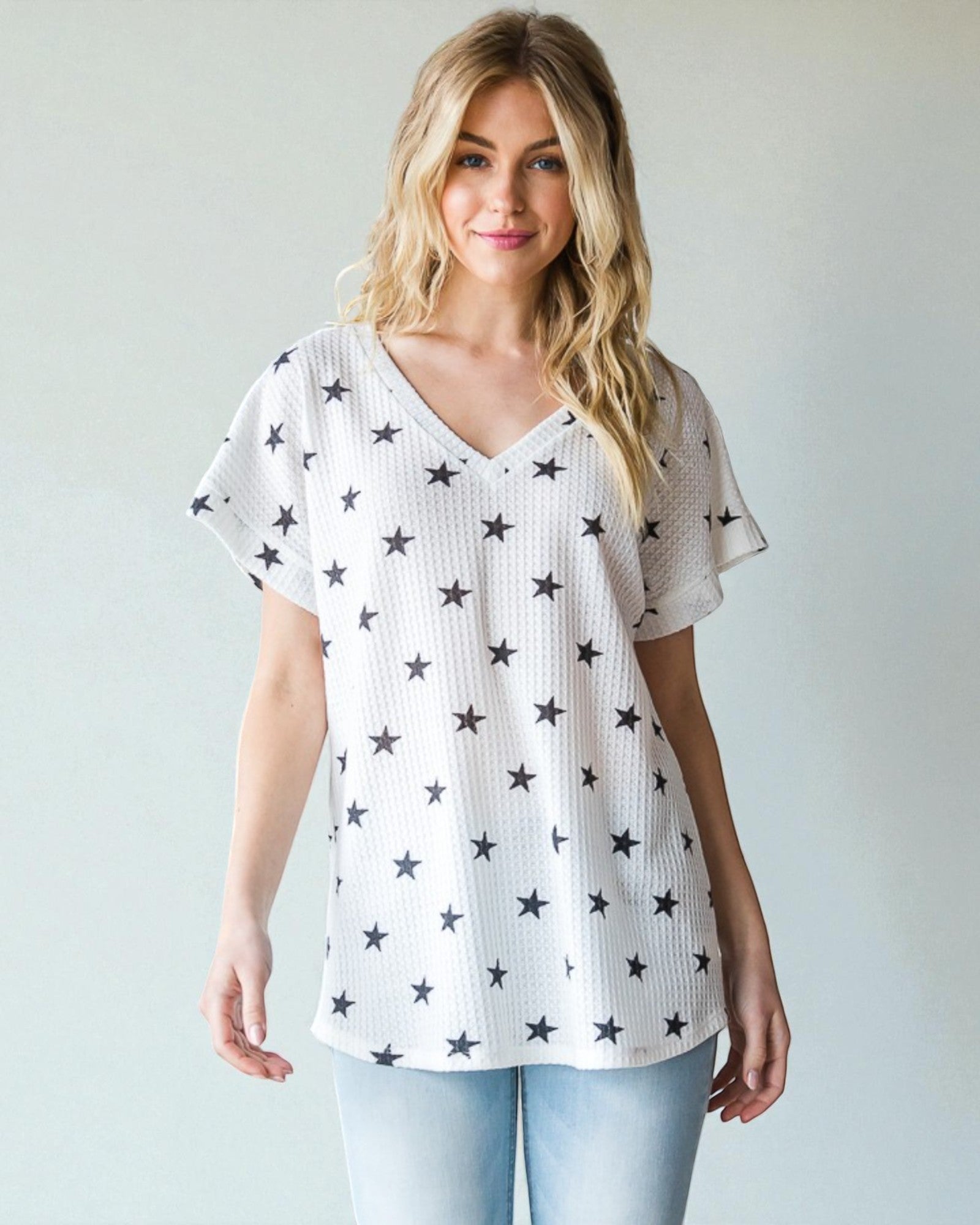 Woman wearing a white t-shirt with star patterns against a plain background