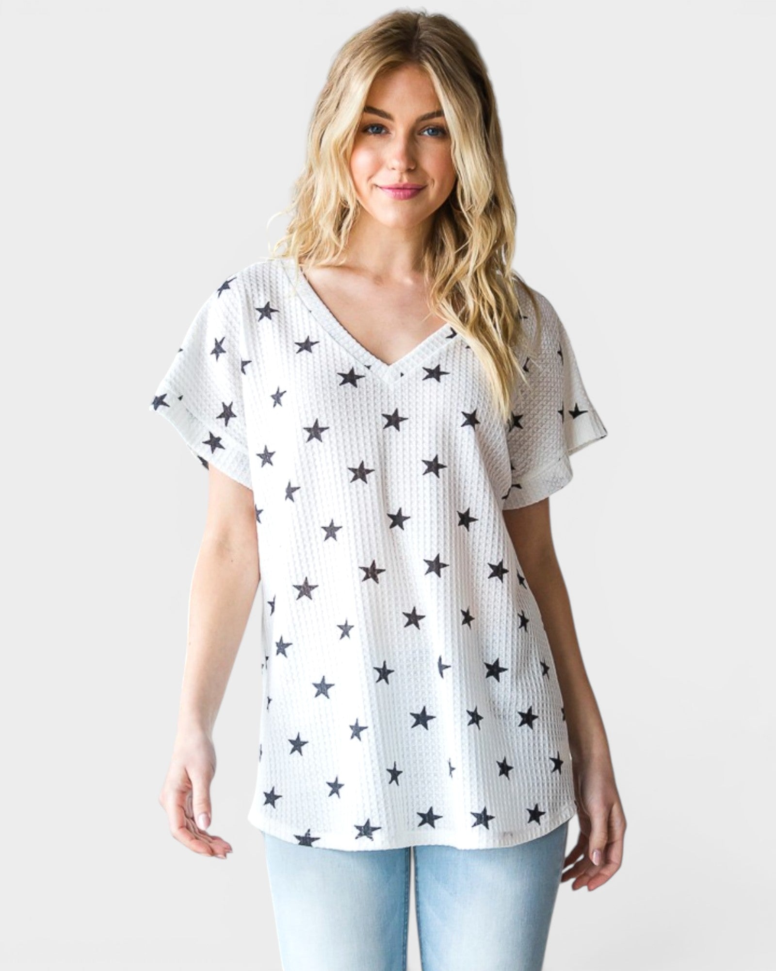 Woman wearing a white t-shirt with star patterns on a plain background