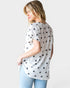 Woman wearing a white t-shirt with black star patterns on a plain background